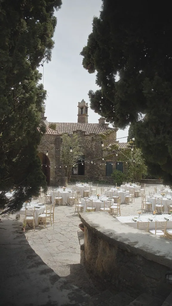 Dinner tables in the stone court at La Baronia, framed by cypress